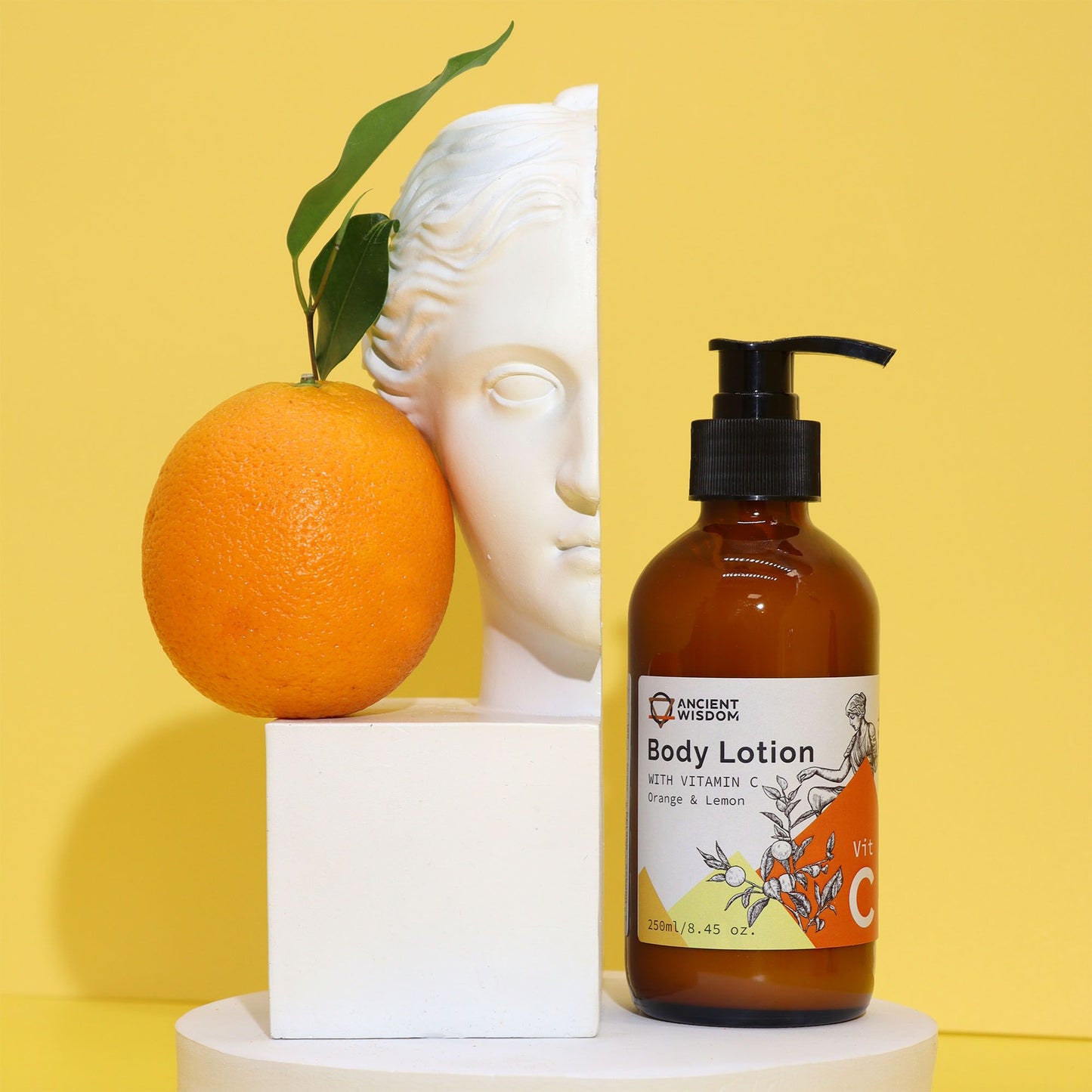 Eine braune Flasche mit Vitamin-C-Körperlotion, Orange und Zitrone, neben einer Statue und einer Orange.