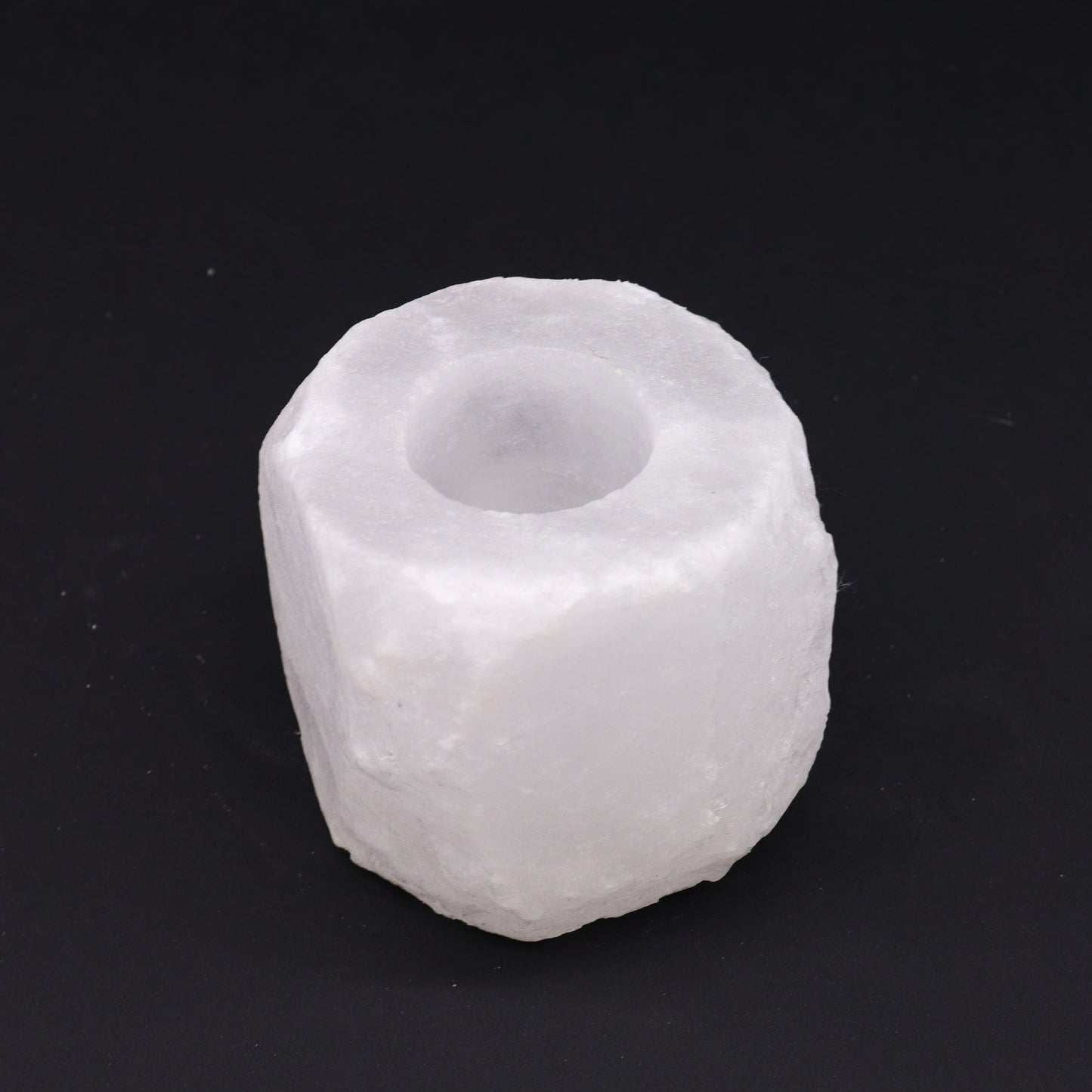 A rough-hewn, white Himalayan salt candle holder with a carved-out top.