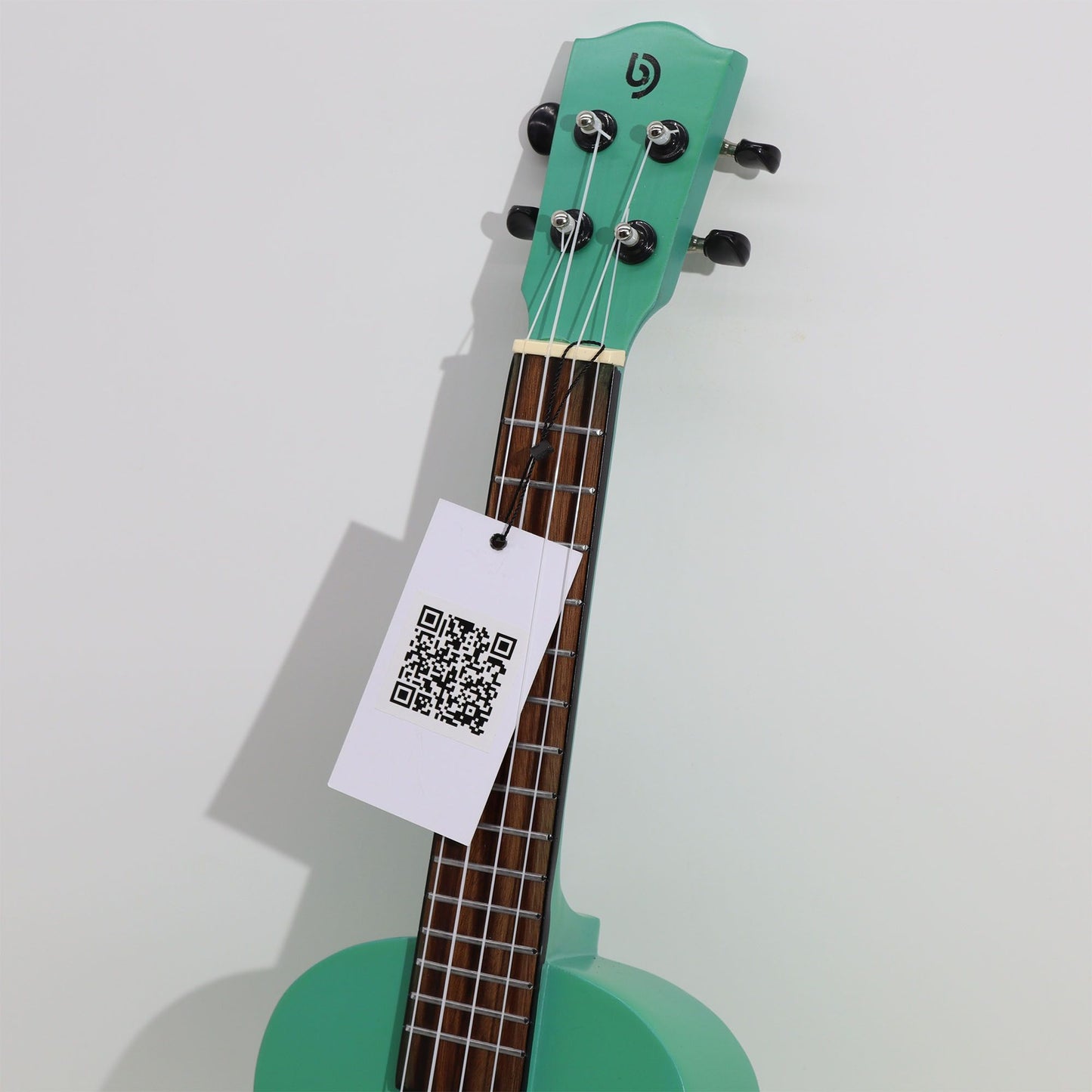 Türkisblaue Ukulele mit schwarzem Logo und QR-Code-Anhänger.