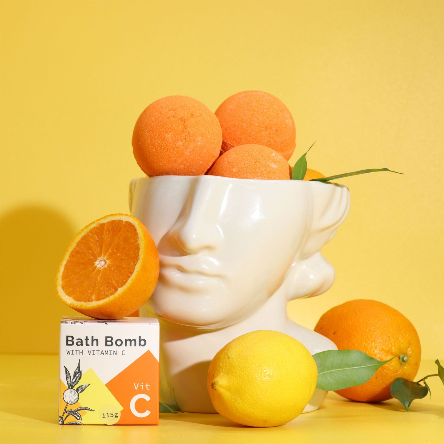 Badebombe mit Vitamin C in einer Büste mit Orangen und Zitrone.