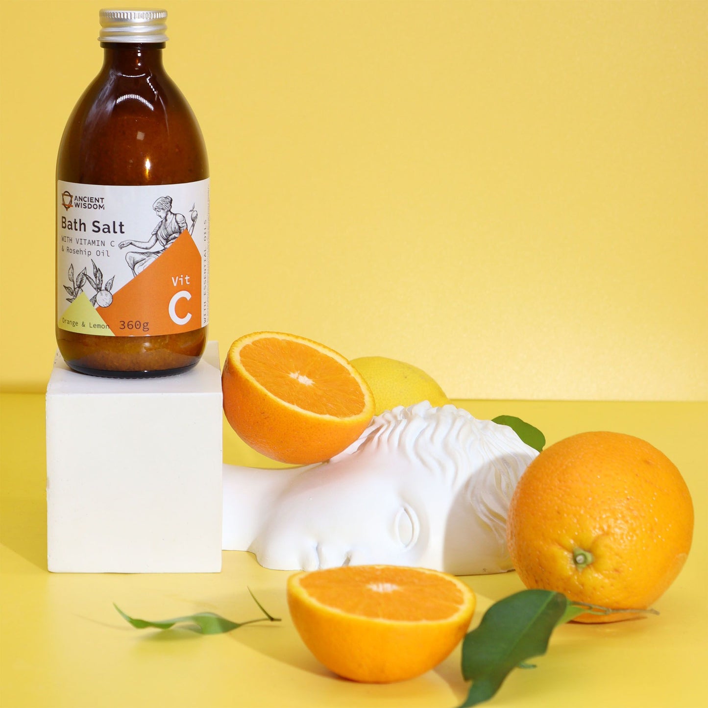 Braune Glasflasche mit Vitamin C Badesalz, Orangen und Zitronen.