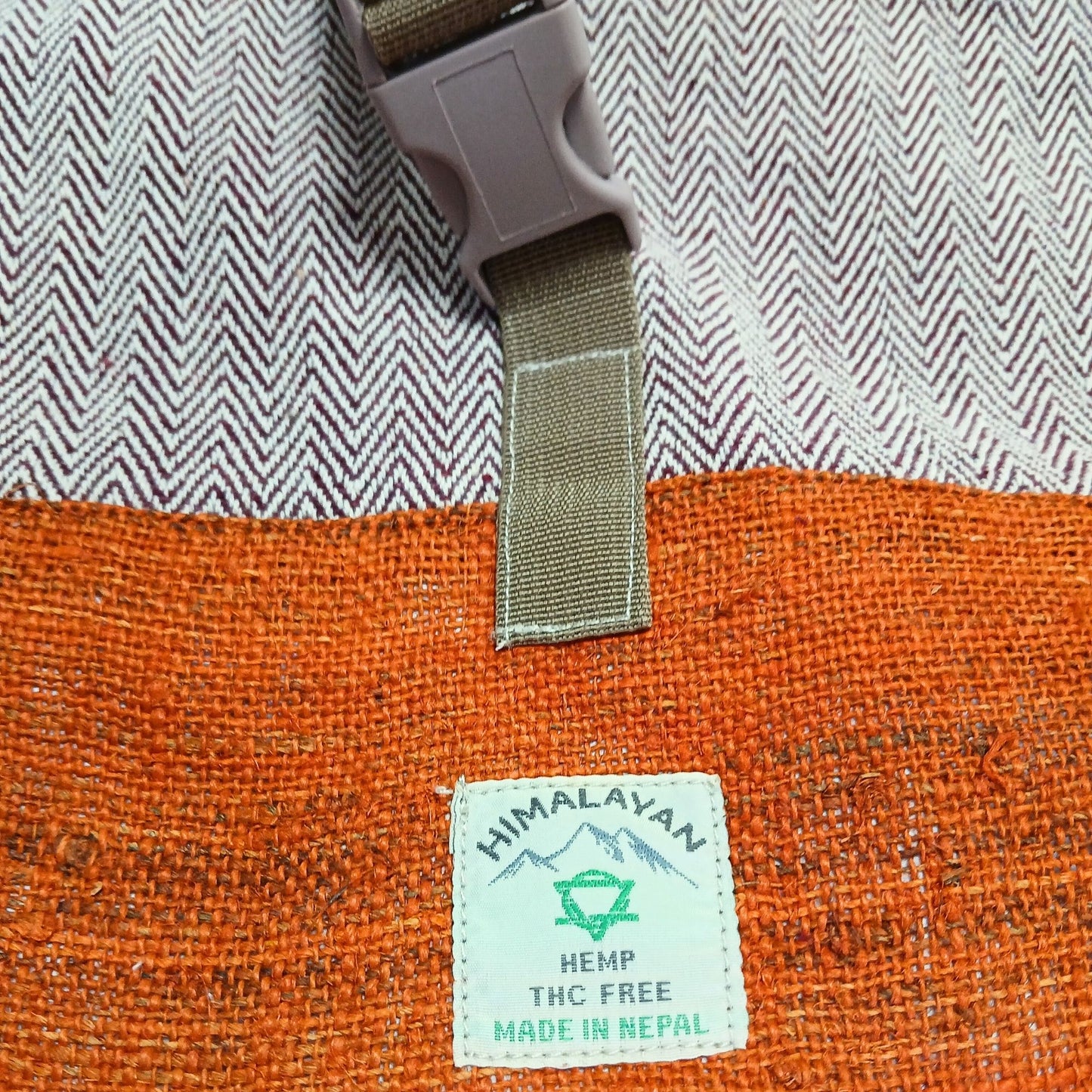 Ein orangefarbener Hanf-Rucksack mit einem "Himalayan Hemp" Etikett und einem Schnallenverschluss.