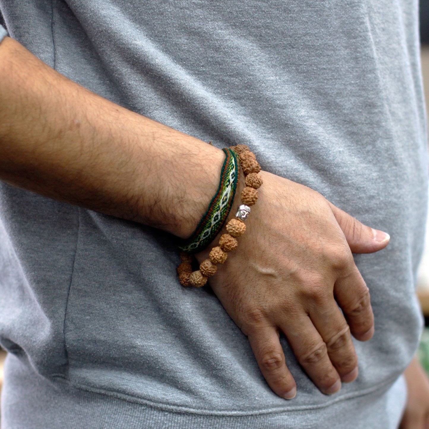 Rudraksha mala bracelet with a Buddha charm and a woven band.