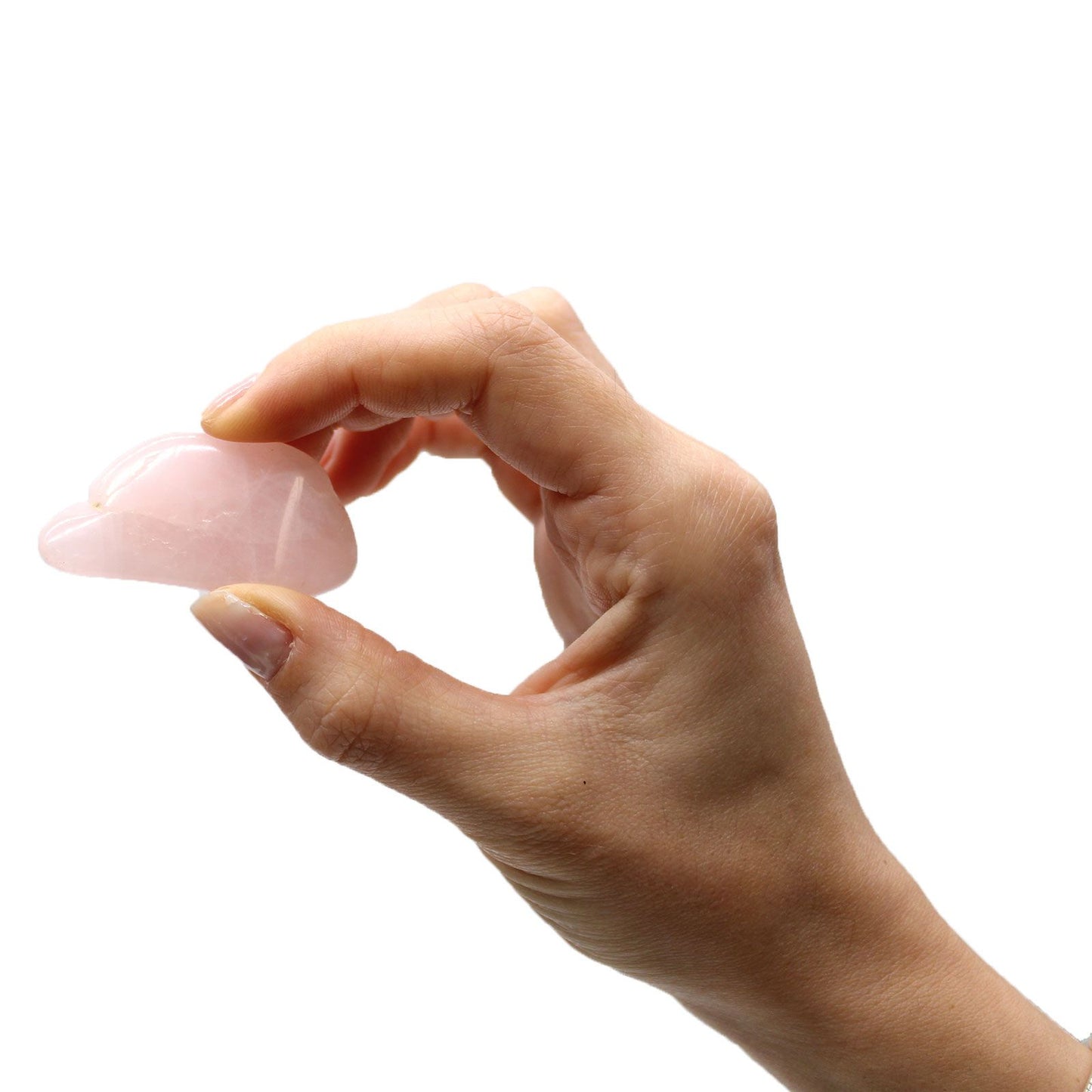 A hand holds a small, smooth, pink rose quartz stone shaped like a cloud.