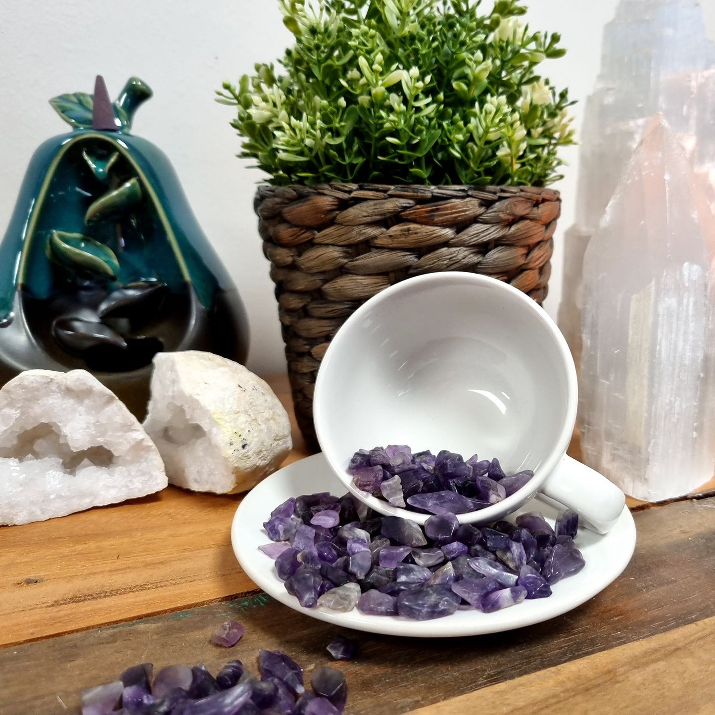 Tumbled lapis lazuli chips in a white teacup on a saucer.