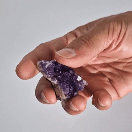 Kleiner natürlicher Amethyst-Cluster in Hand gehalten