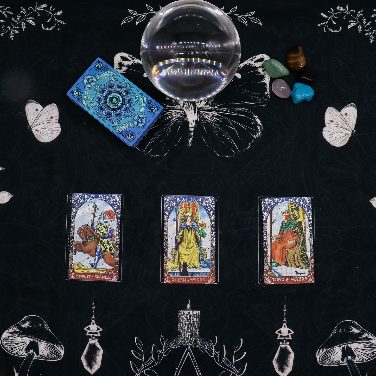 Tarot reading cloth with a crystal ball, tarot cards, and crystals on a black background.