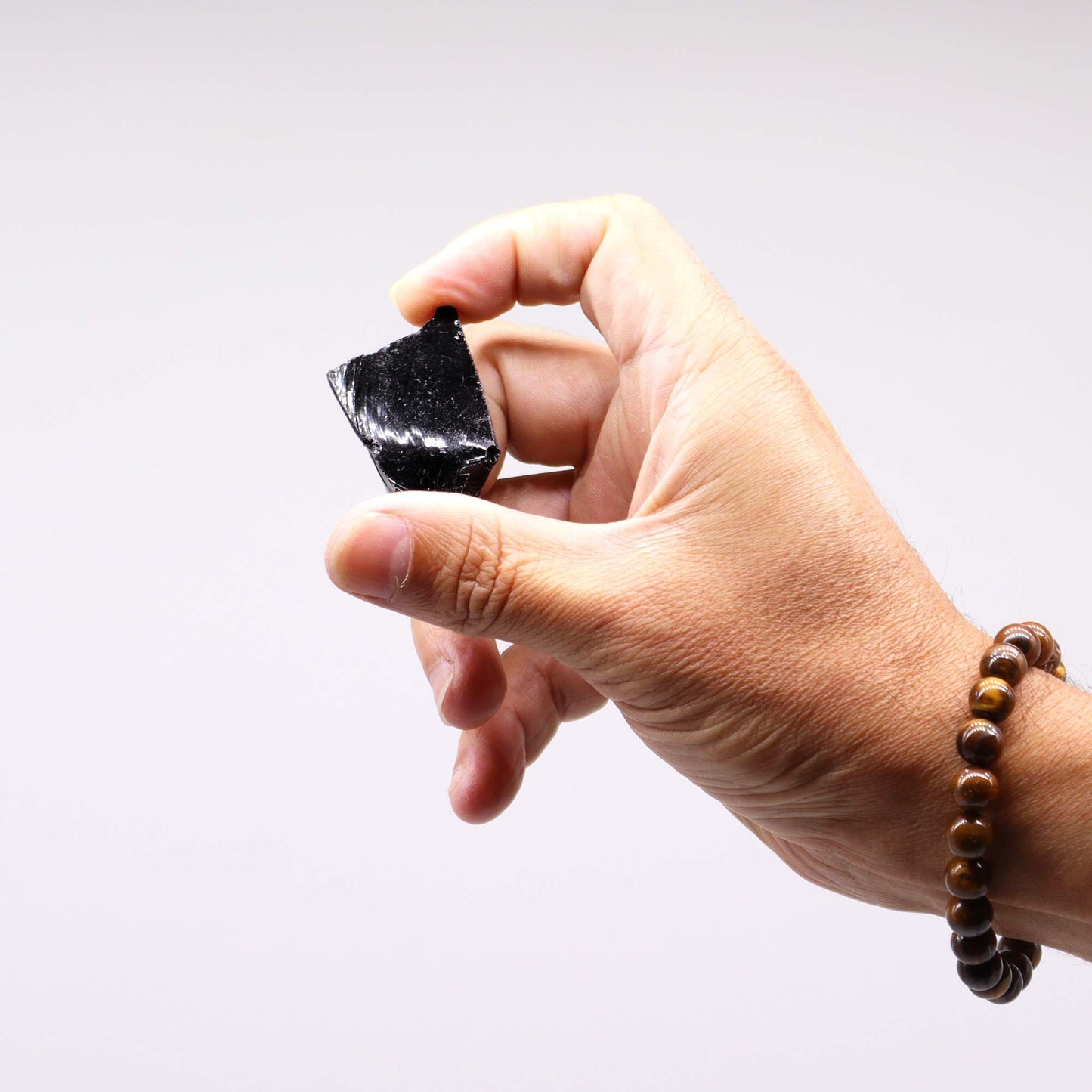 Ein Mensch hält einen rohen schwarzen Obsidianstein in der Hand.