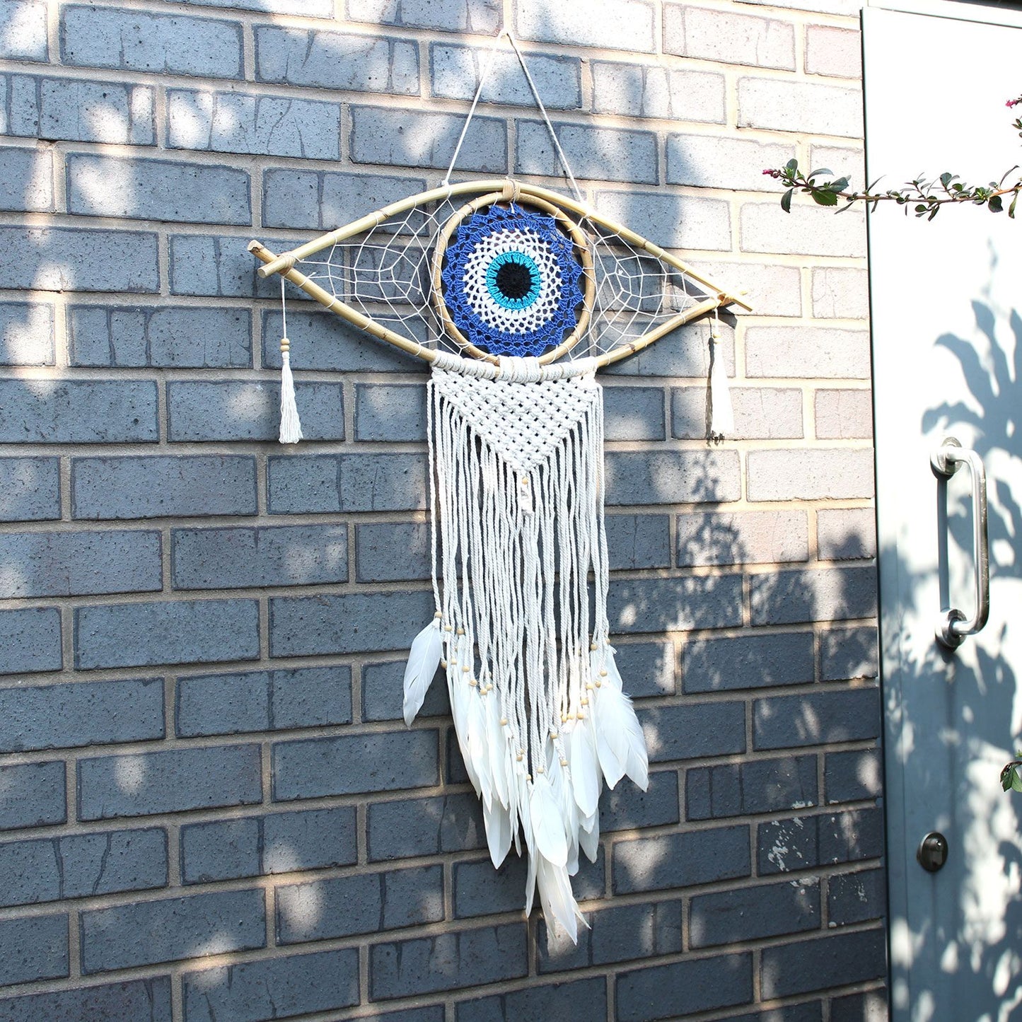 XL Makramee Traumfänger in Augenform mit blauen und weißen Häkeldetails und Federn.