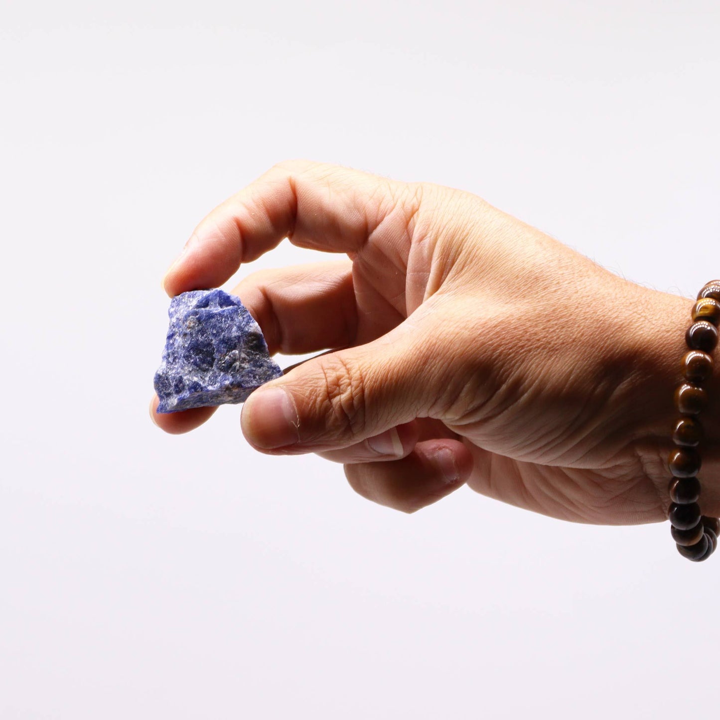 Ein Mensch hält einen rohen, tiefblauen Sodalithstein in der Hand.