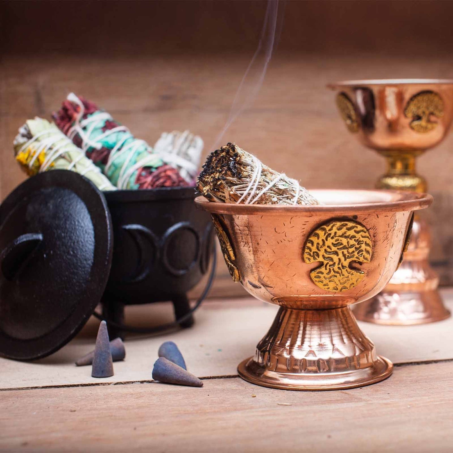 Kupferner Ritualkelch mit Lebensbaum-Motiv, gefüllt mit Räucherstäbchen.