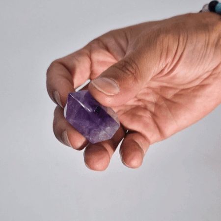 Eine natürliche Amethyst-Kristallspitze in der Hand.