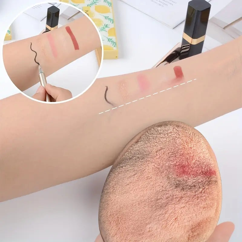 Ein weiches Mikrofaser-Abschminkpad entfernt Make-up-Swatches sanft von einem Unterarm.