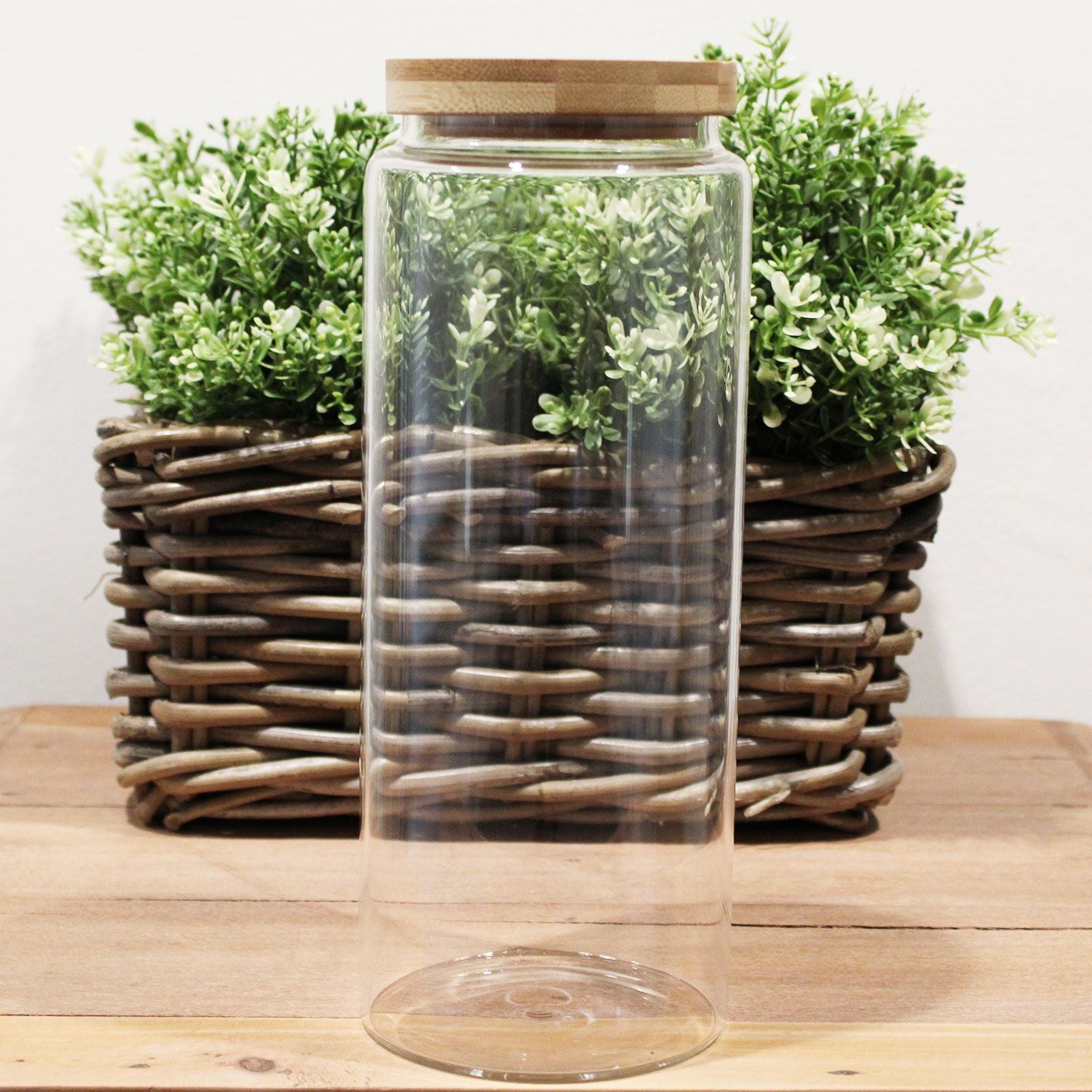 Vorratsglas aus Glas mit Bambusdeckel und grünen Pflanzen.