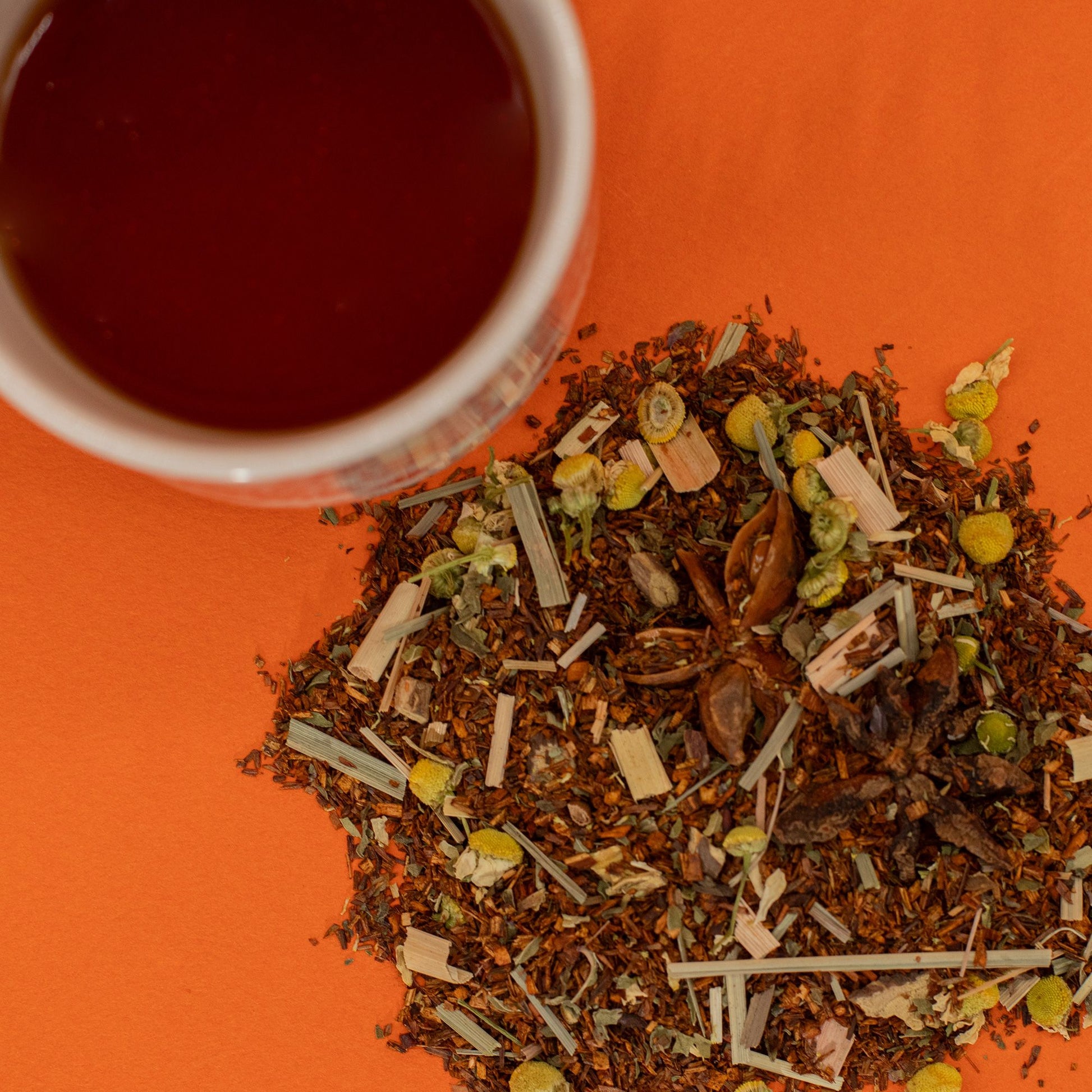 A cup of rooibos tea sits next to a pile of organic biodigest rooibos tea leaves.