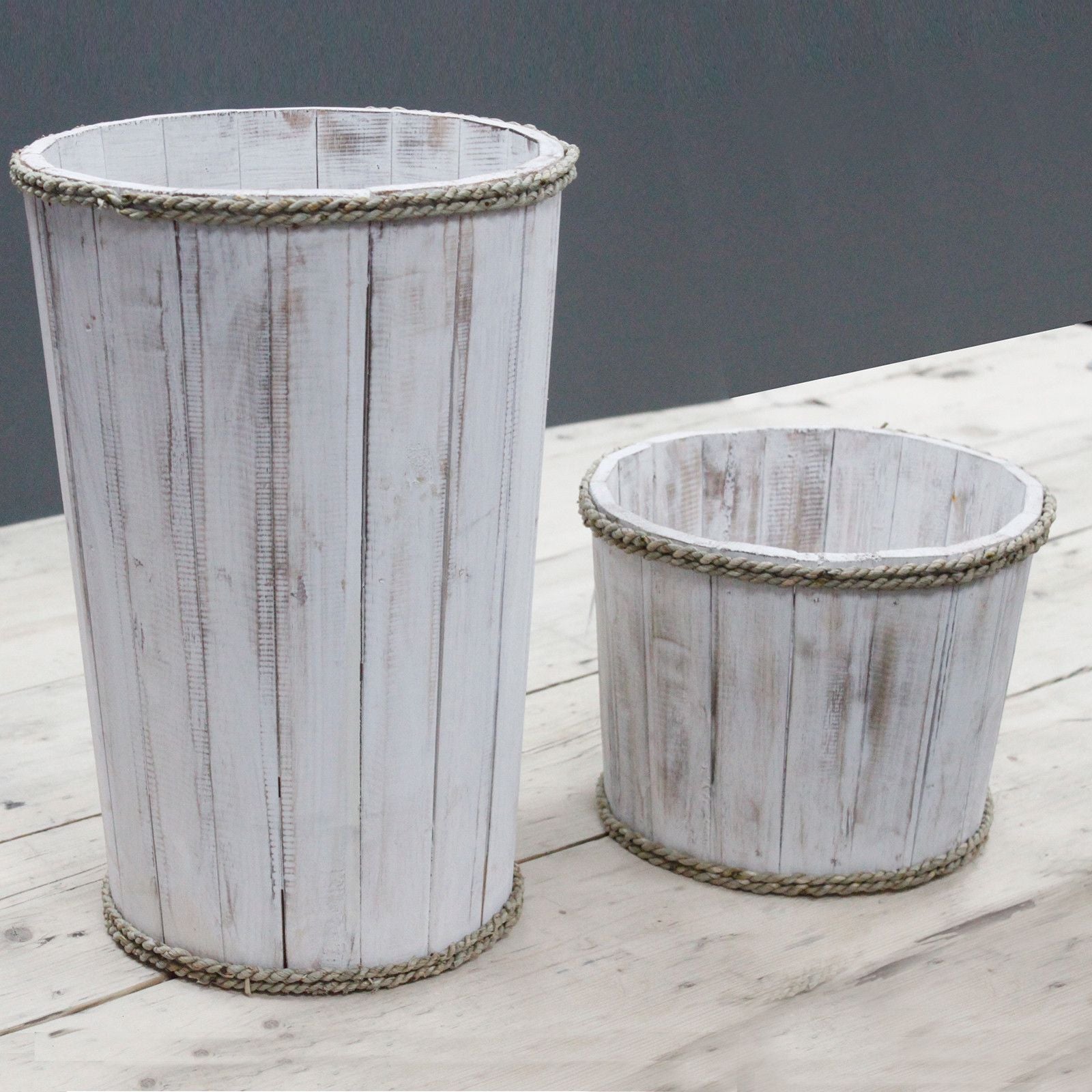 Two whitewashed wooden tubs with rope trim on a wooden surface.