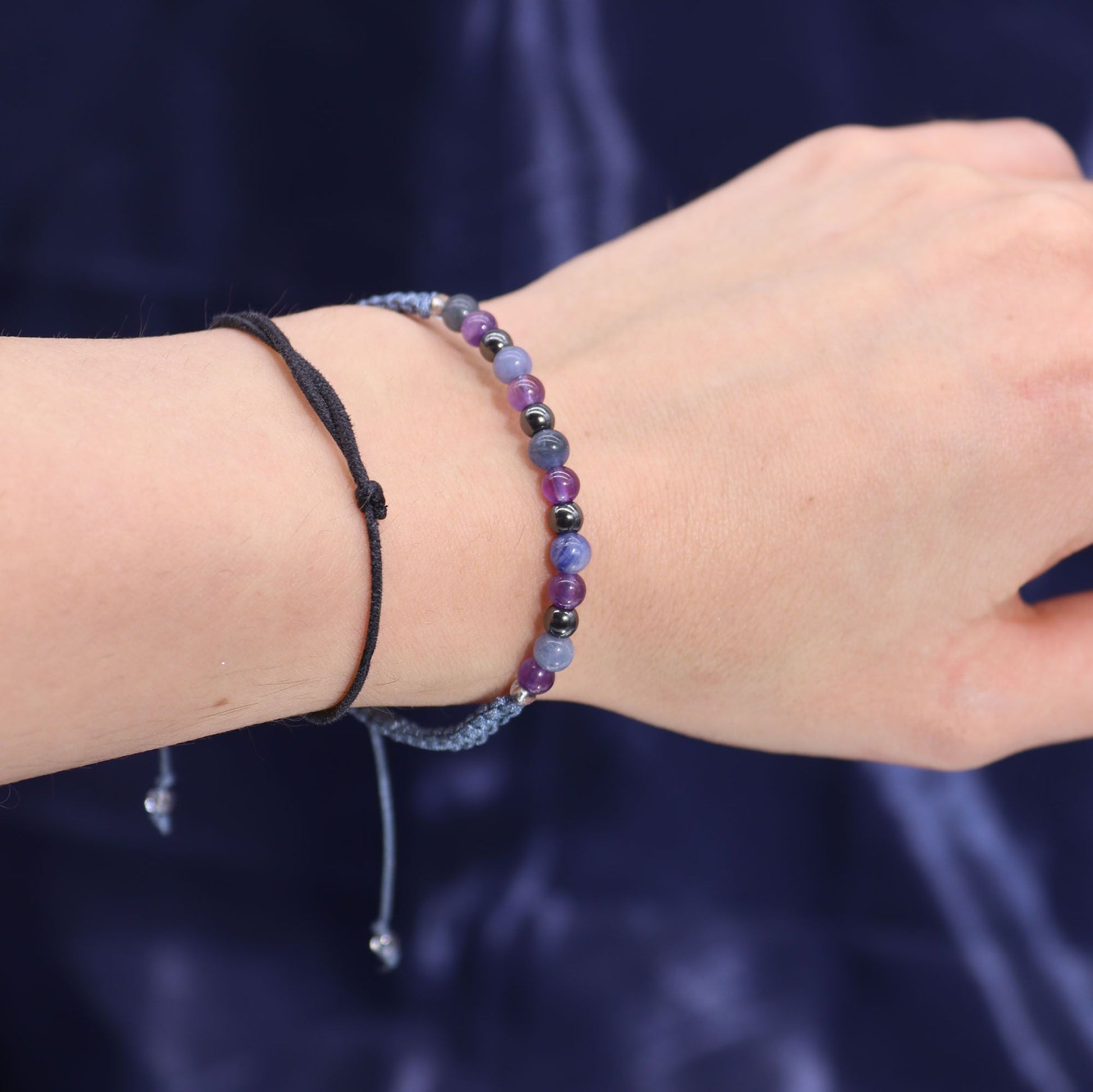 Armband mit lila und blauen Perlen und einem schwarzen Band.
