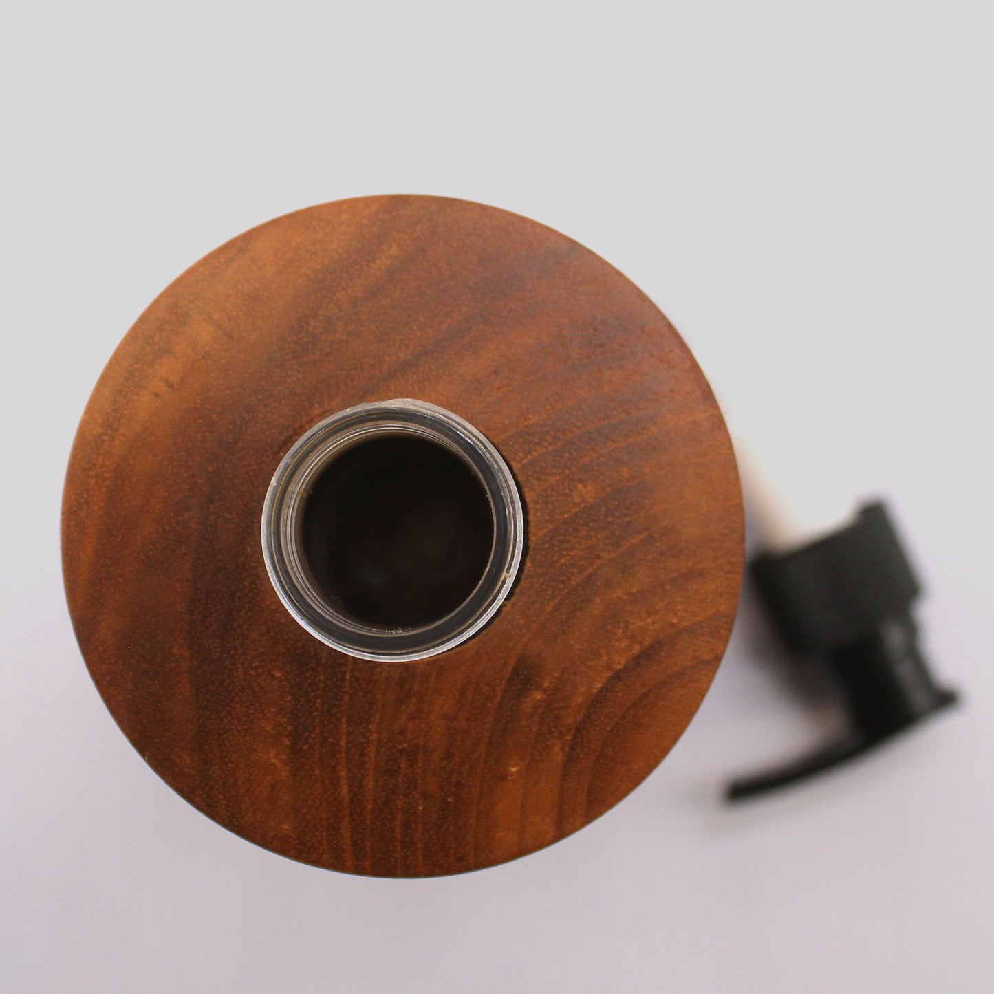 Natural teakwood soap dispenser with a clear glass opening and black pump.
