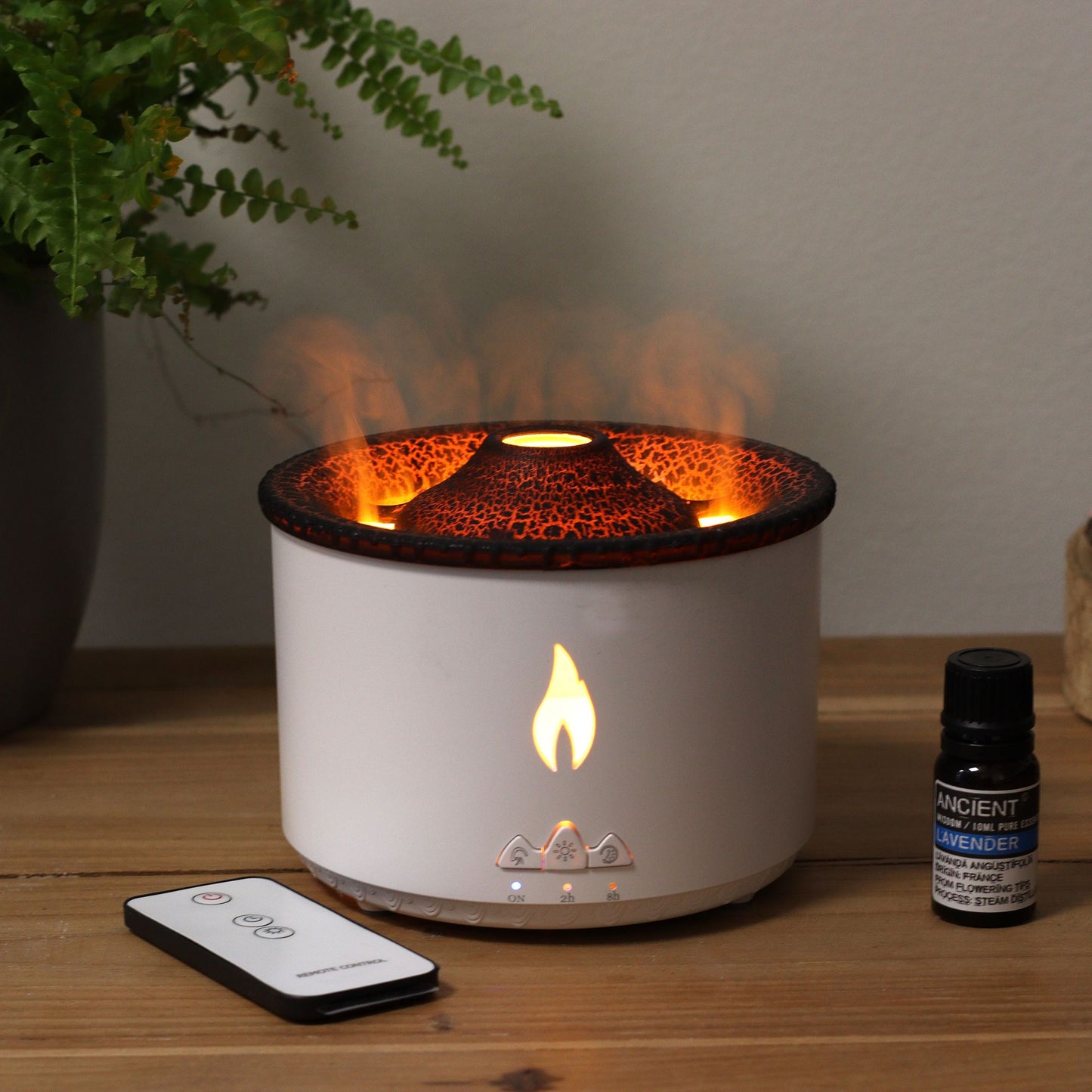 A white volcano effect aroma diffuser with a remote control and a bottle of lavender essential oil.