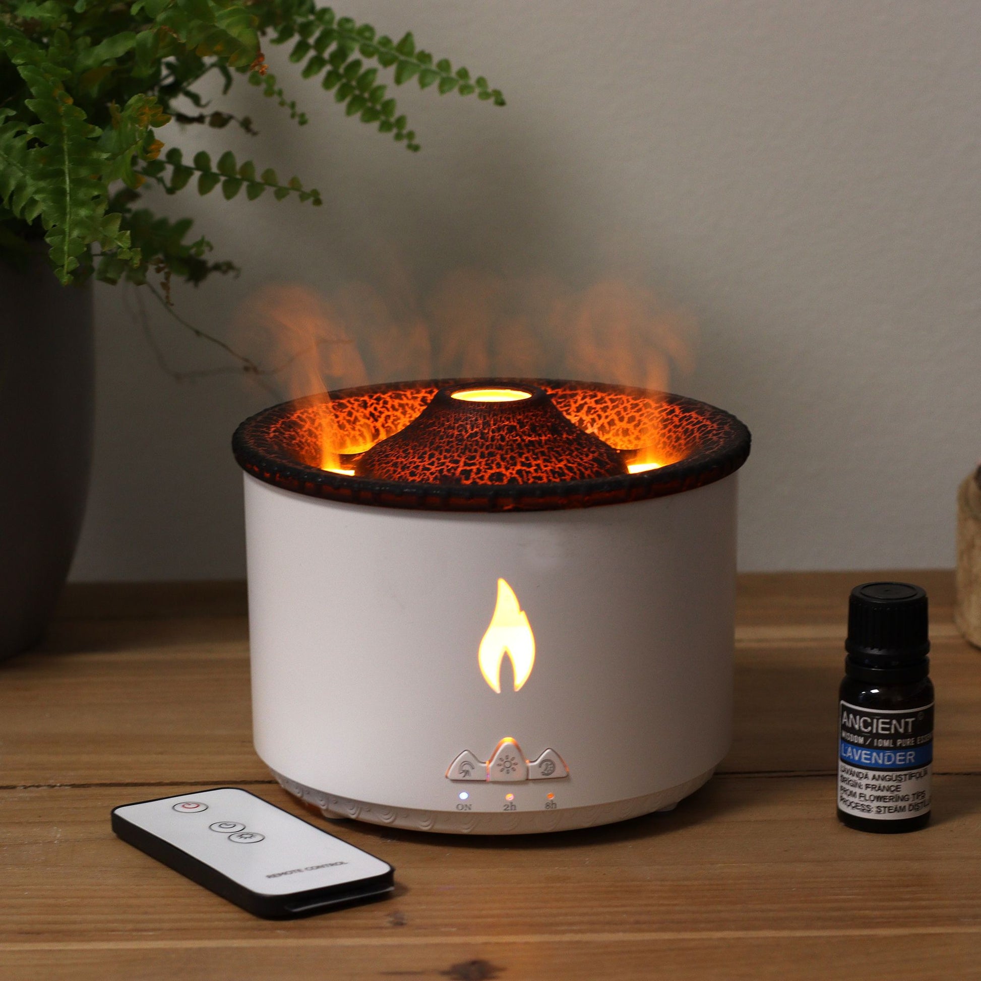 A white volcano effect aroma diffuser with a remote control and a bottle of lavender essential oil.