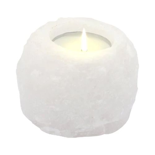 A white Himalayan salt candle holder with a lit candle inside.