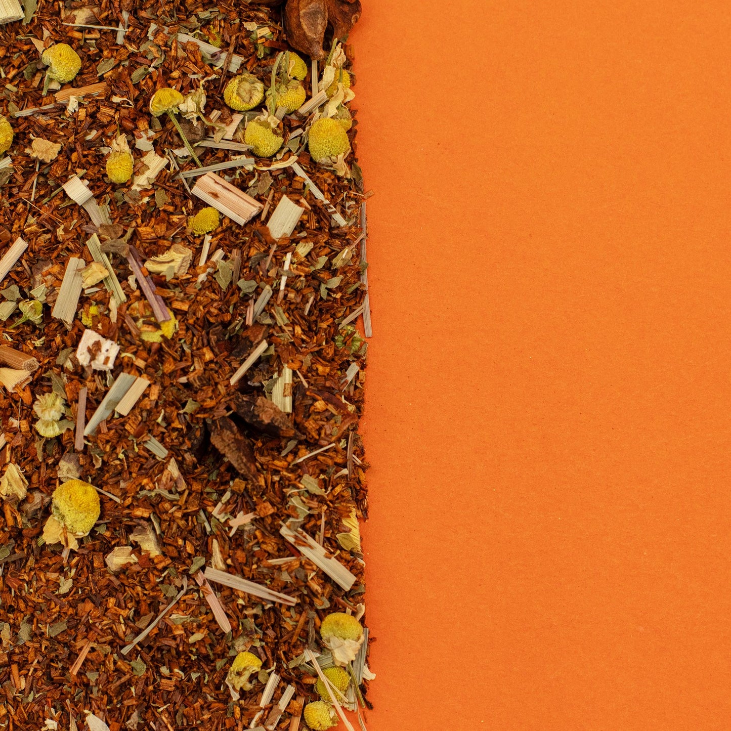 Organic rooibos tea blend with chamomile and lemongrass on an orange background.