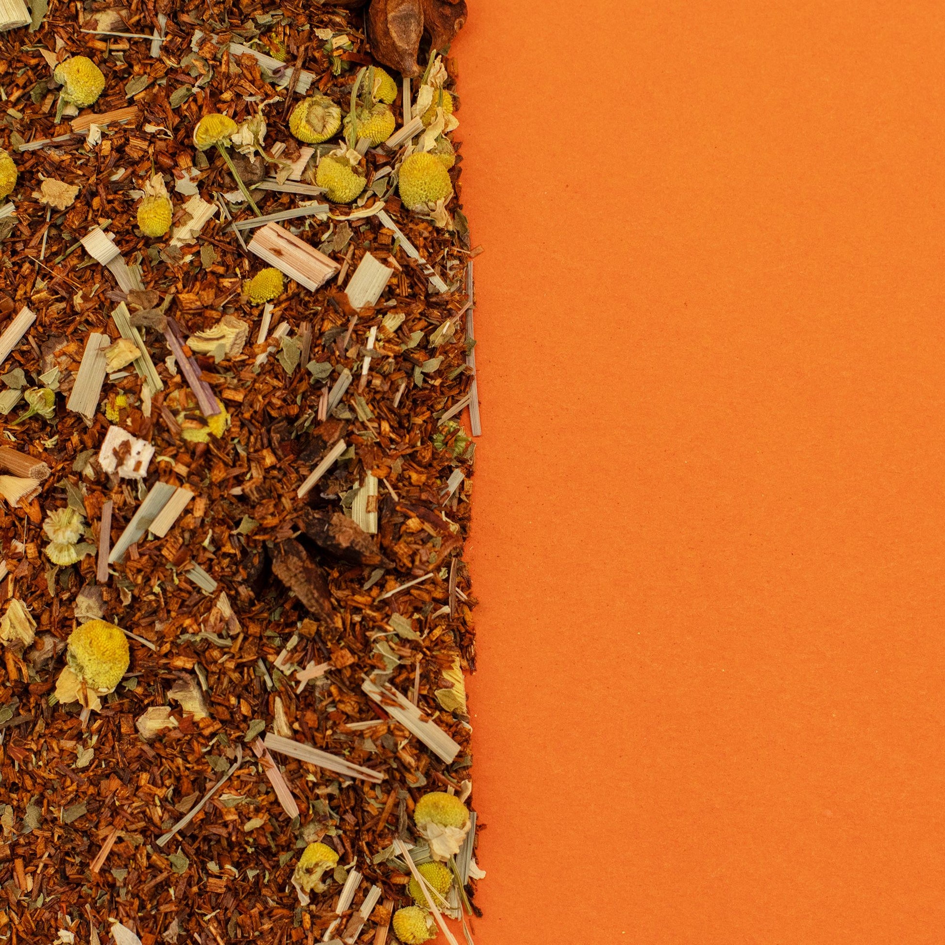 Organic rooibos tea blend with chamomile and lemongrass on an orange background.