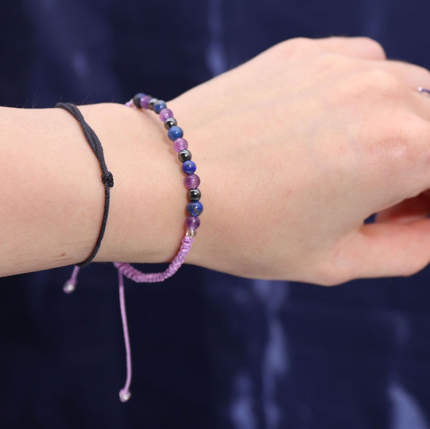 Armband mit lila und blauen Perlen und einem schwarzen Band.