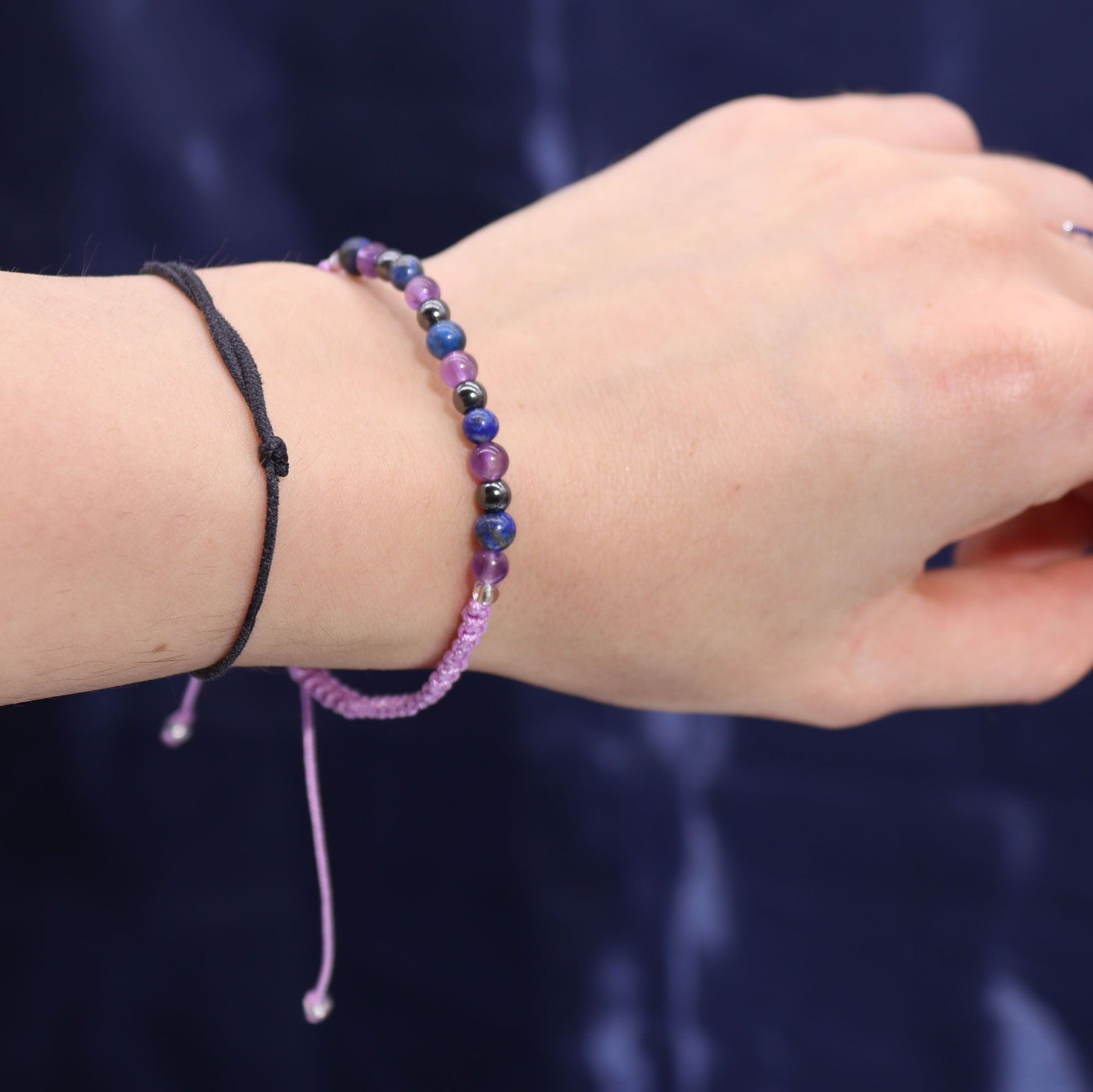 Armband mit lila und blauen Perlen und einem schwarzen Band.