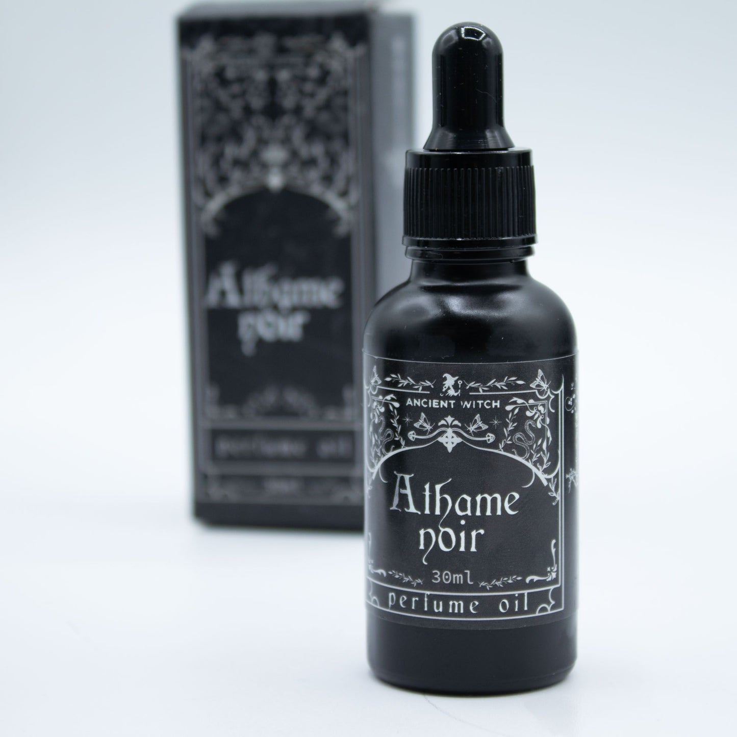 A black bottle of Athame Noir perfume oil with a dropper top.