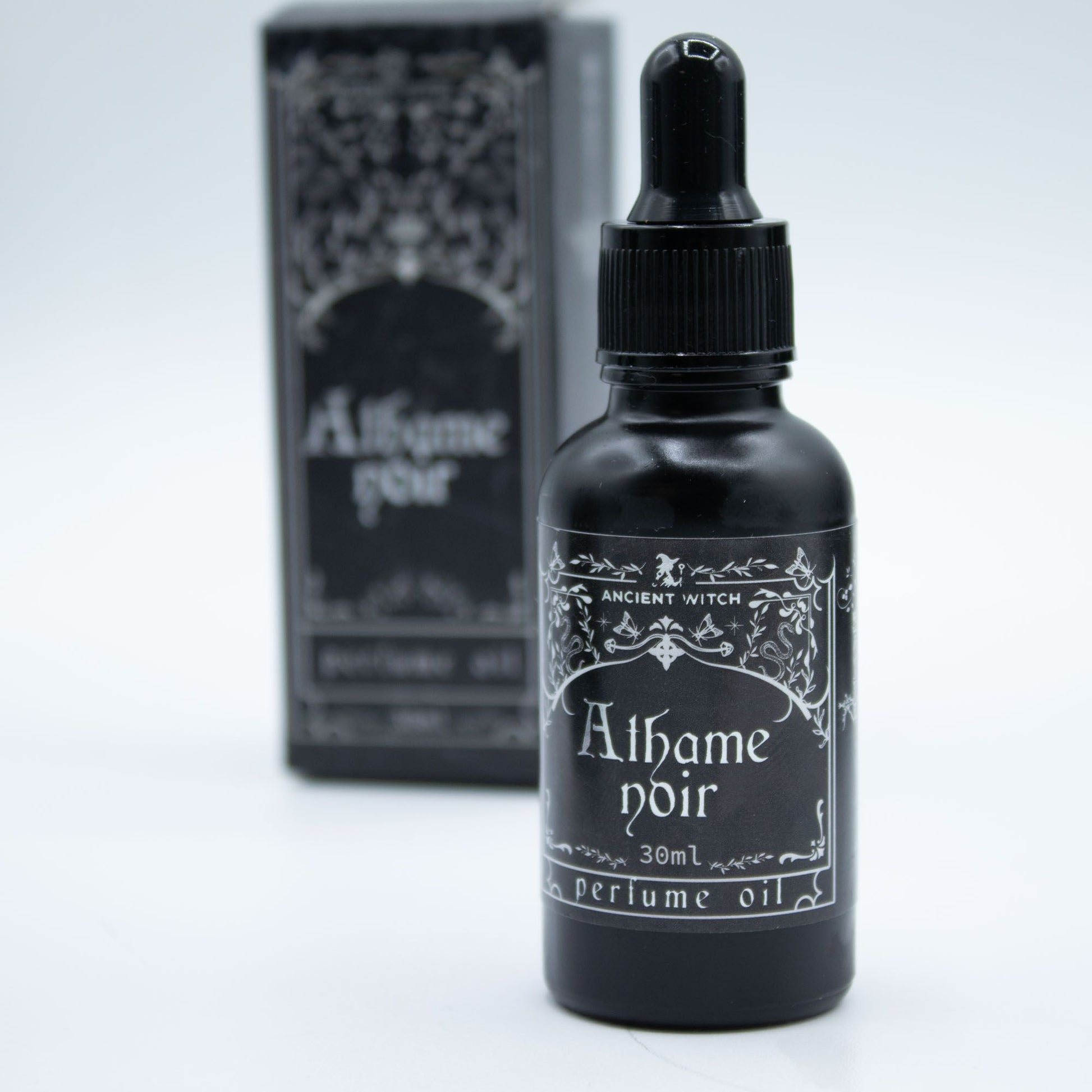 A black bottle of Athame Noir perfume oil with a dropper top.