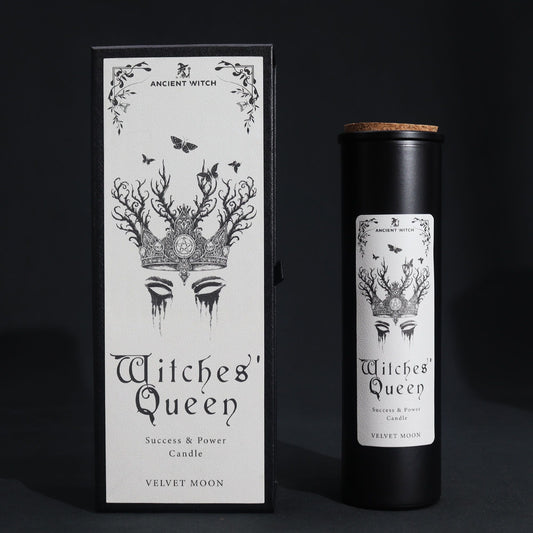 A black candle in a cylindrical container with a label featuring a crown and the text "Witches' Queen".
