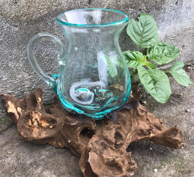 Handgefertigte Karaffe aus recyceltem Glas auf Wurzelholz.