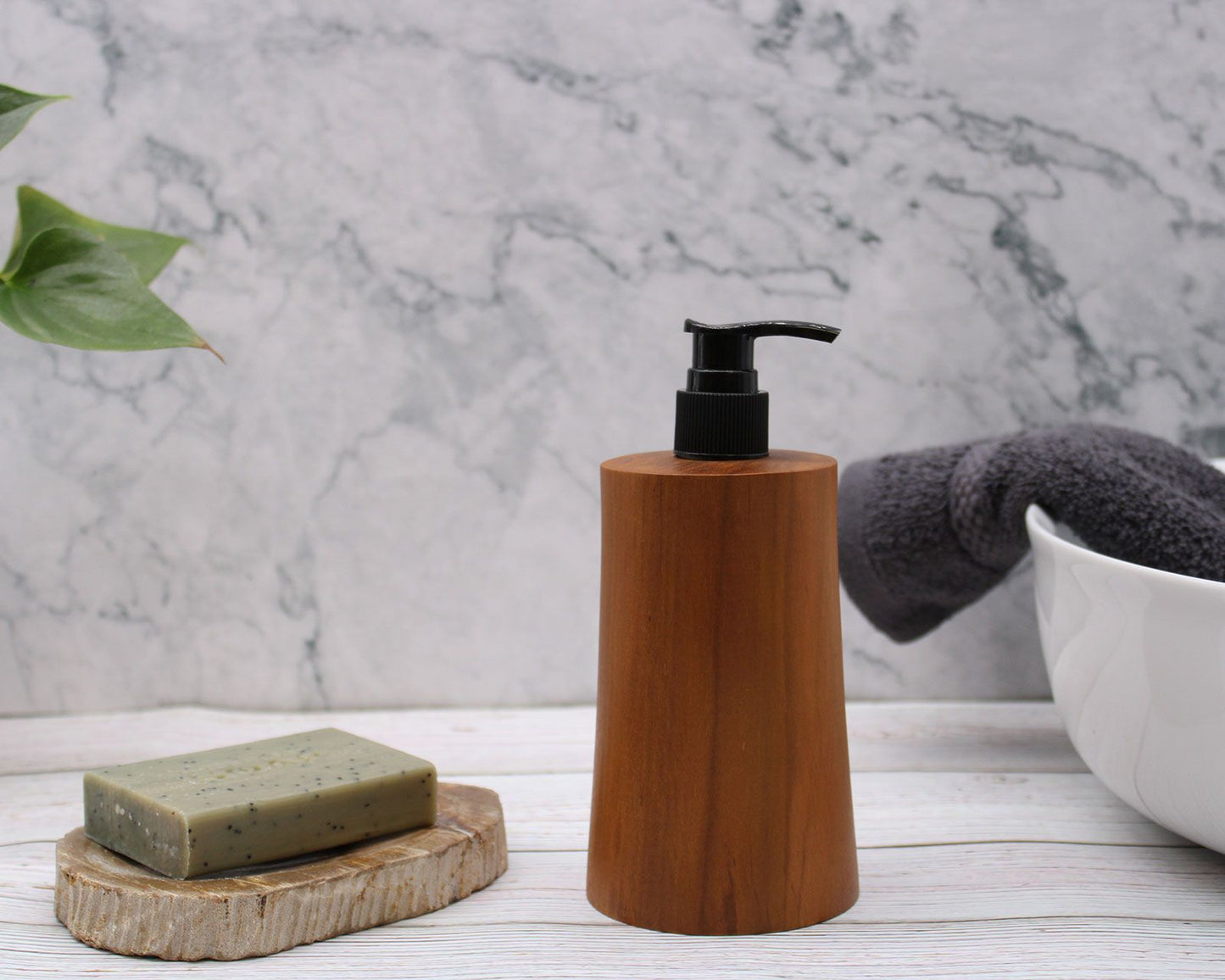Natural teakwood soap dispenser with a black pump next to a bar of soap.