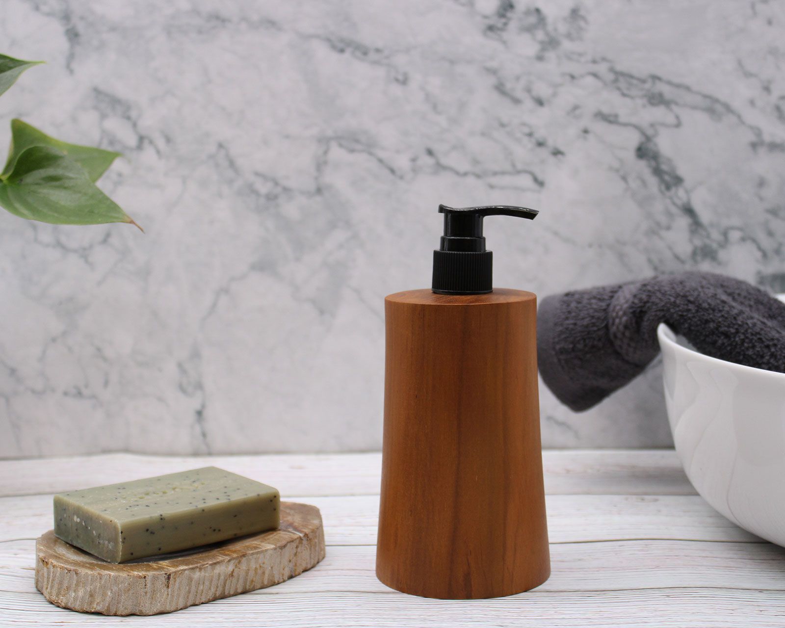 Natural teakwood soap dispenser with a black pump next to a bar of soap.