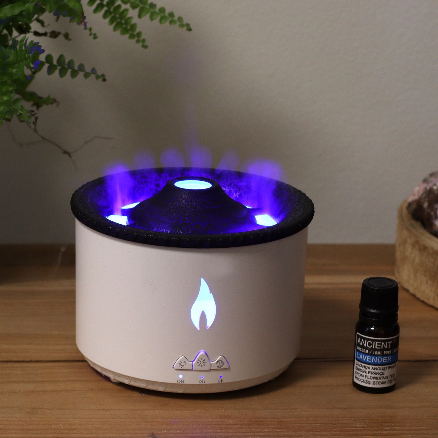 A white volcano-shaped aroma diffuser with blue flame effect and a bottle of lavender essential oil.