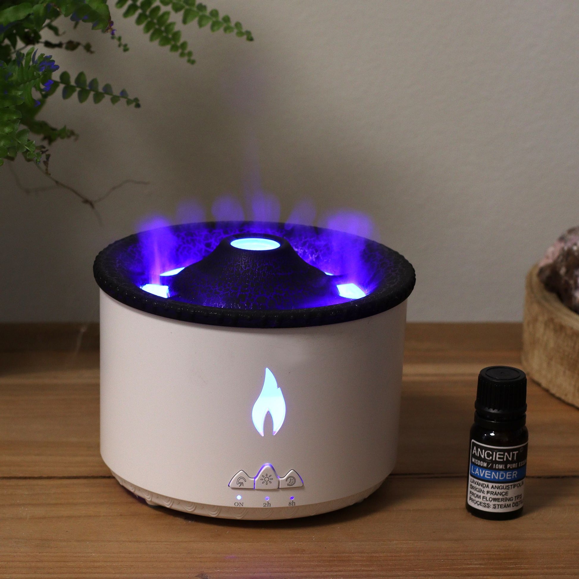 A white volcano-shaped aroma diffuser with blue flame effect and a bottle of lavender essential oil.