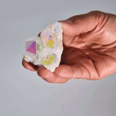 Natürlicher Angel Aura Quarz Cluster mit regenbogenfarbenem Schimmer in einer Hand.
