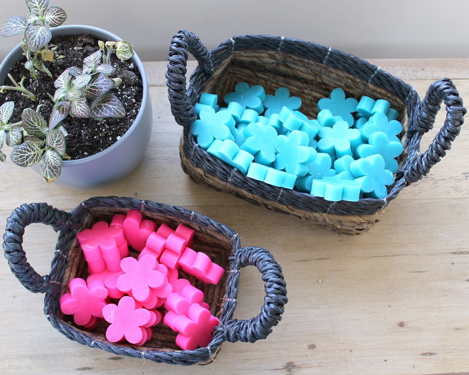 Geflochtene Aufbewahrungskörbe mit blauen und pinken Blumen-Seifen.