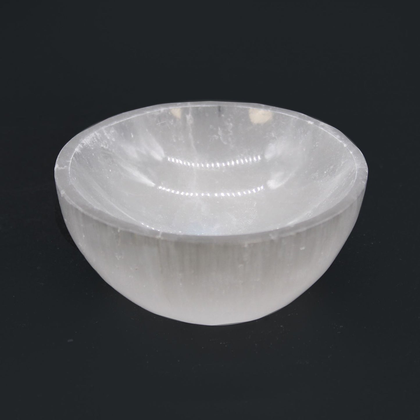 Runde Selenitschale mit 8cm Durchmesser auf schwarzem Hintergrund.