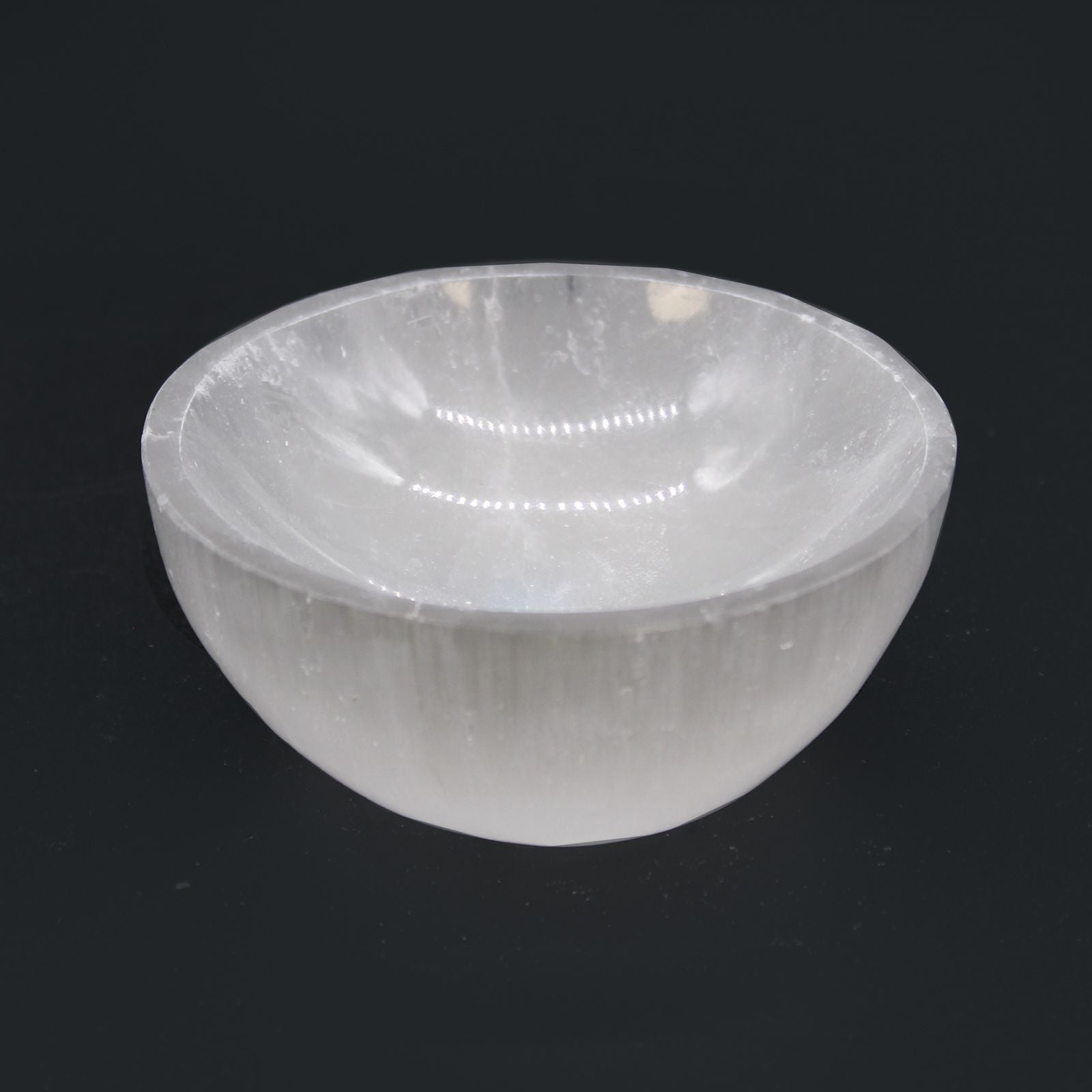 Runde Selenitschale mit 8cm Durchmesser auf schwarzem Hintergrund.