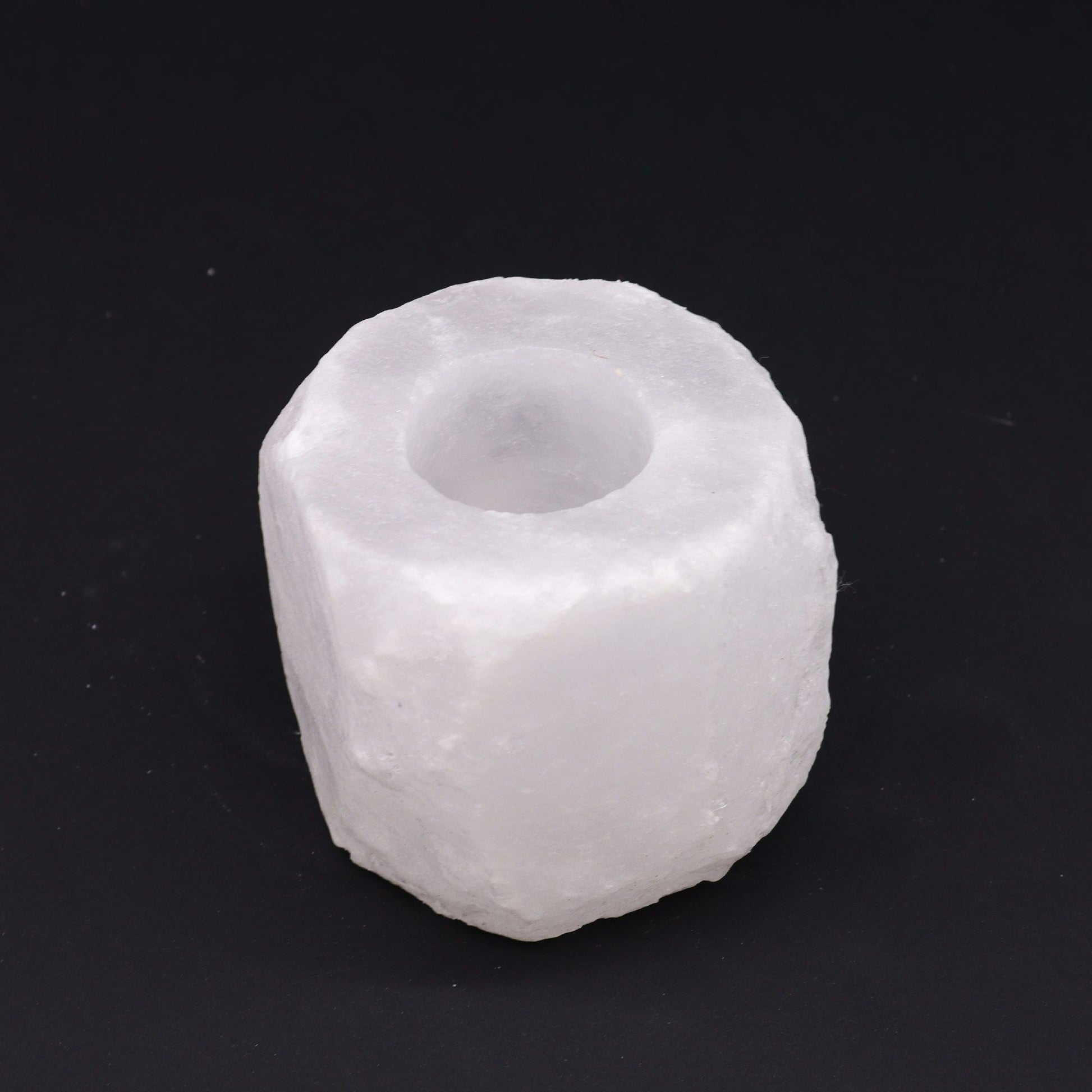 A rough-hewn, white Himalayan salt candle holder with a carved-out top.