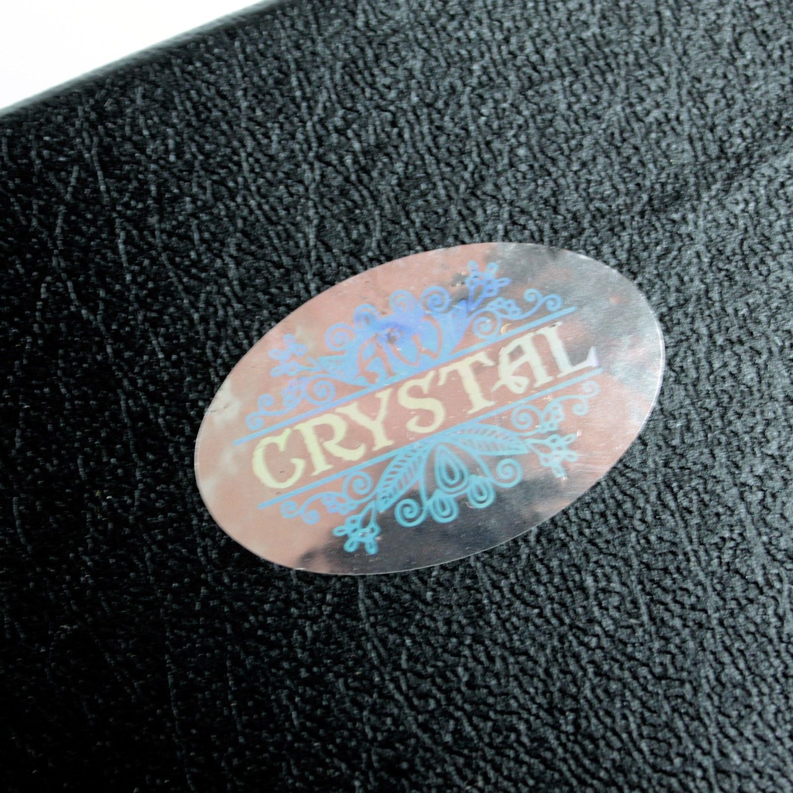 Oval sticker with the word "CRYSTAL" in light yellow and blue decorative elements.