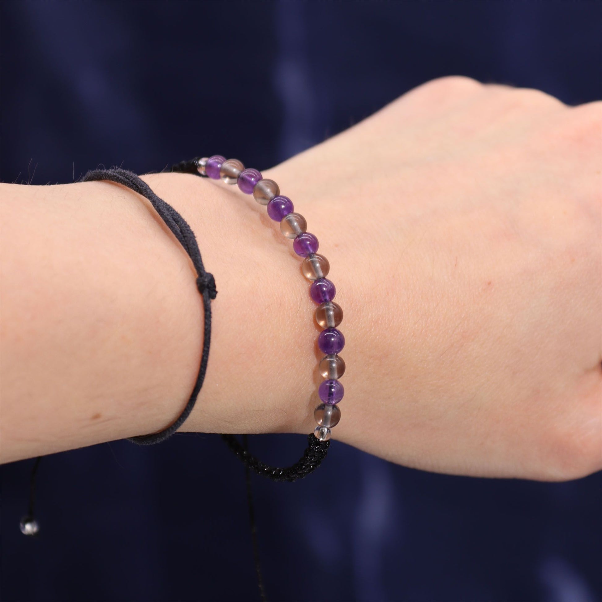 Armband mit lila und braunen Perlen an schwarzem Band.