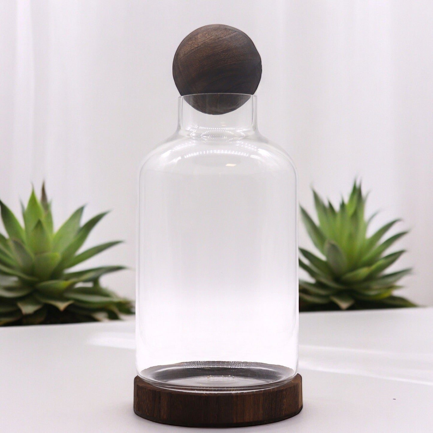 Large glass terrarium with a dark wood ball top and base.