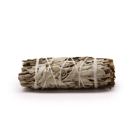 Smudge stick bundle of white sage and pirul foliage tied with white string.