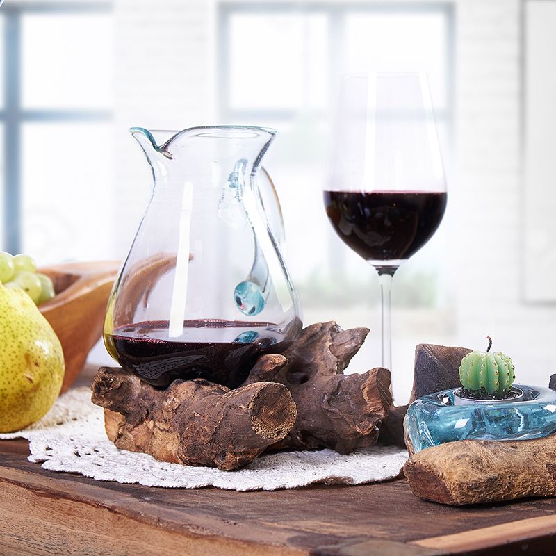 Handgefertigte Karaffe aus recyceltem Glas auf Wurzelholz.