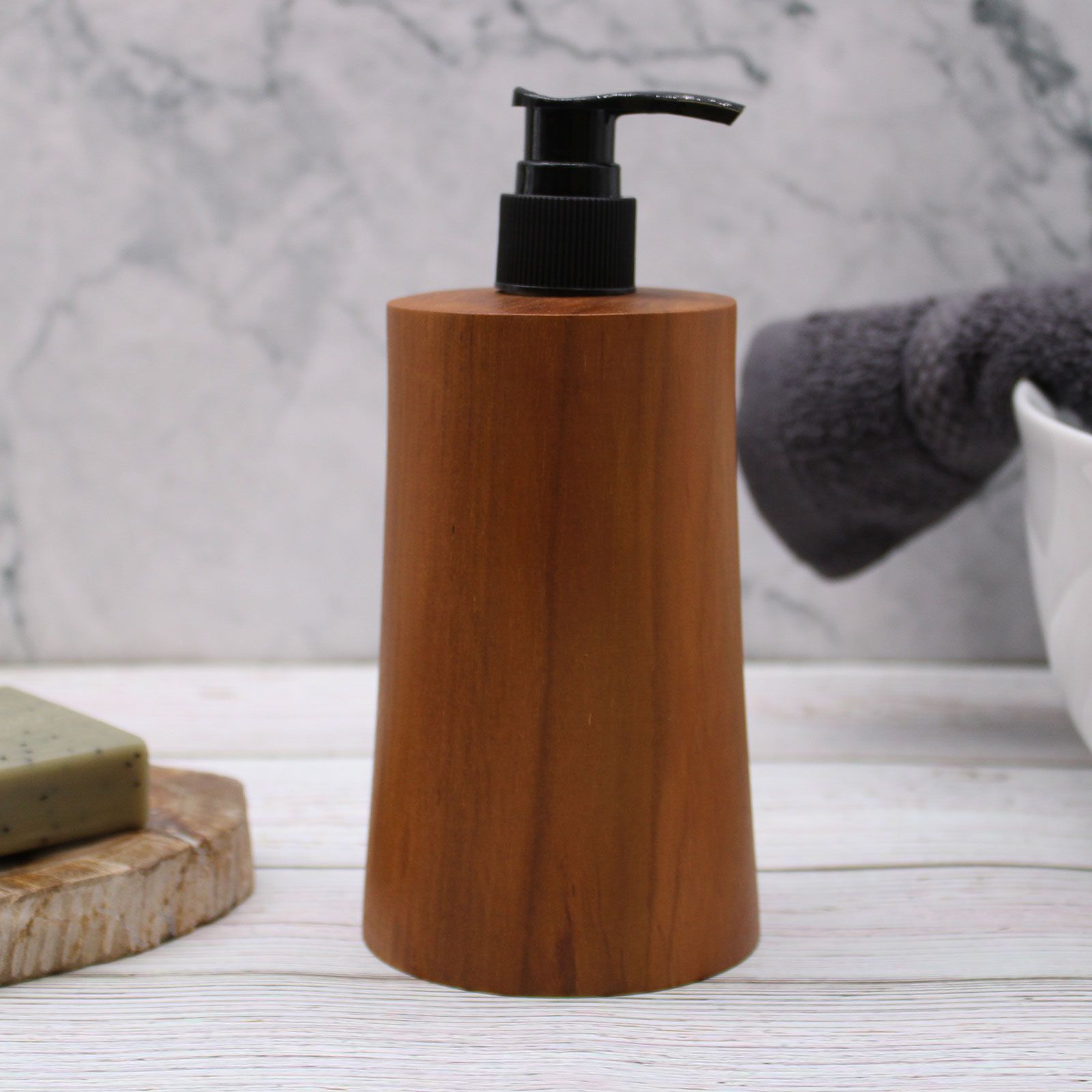 Natural teakwood soap dispenser with a black pump on a white wooden surface.