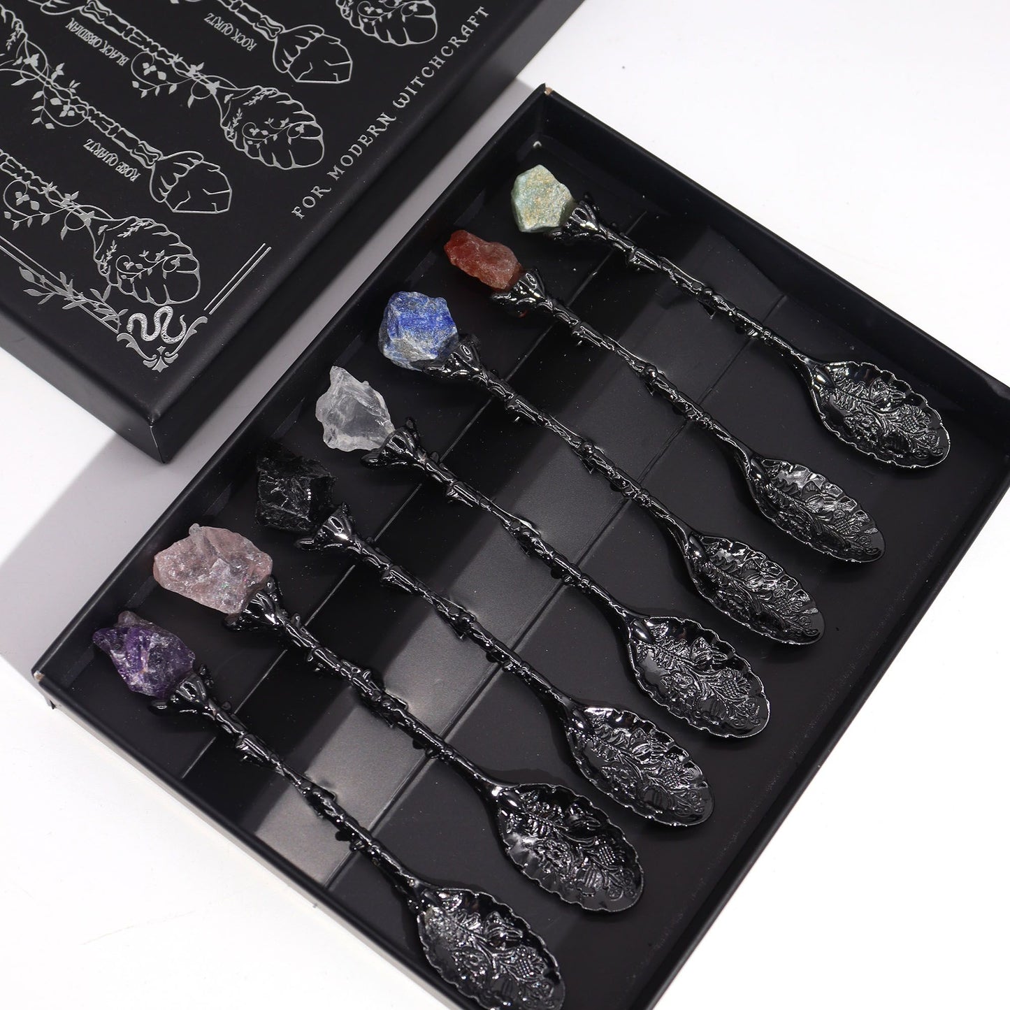 Set of 7 dark silver spoons, each topped with a unique raw gemstone.