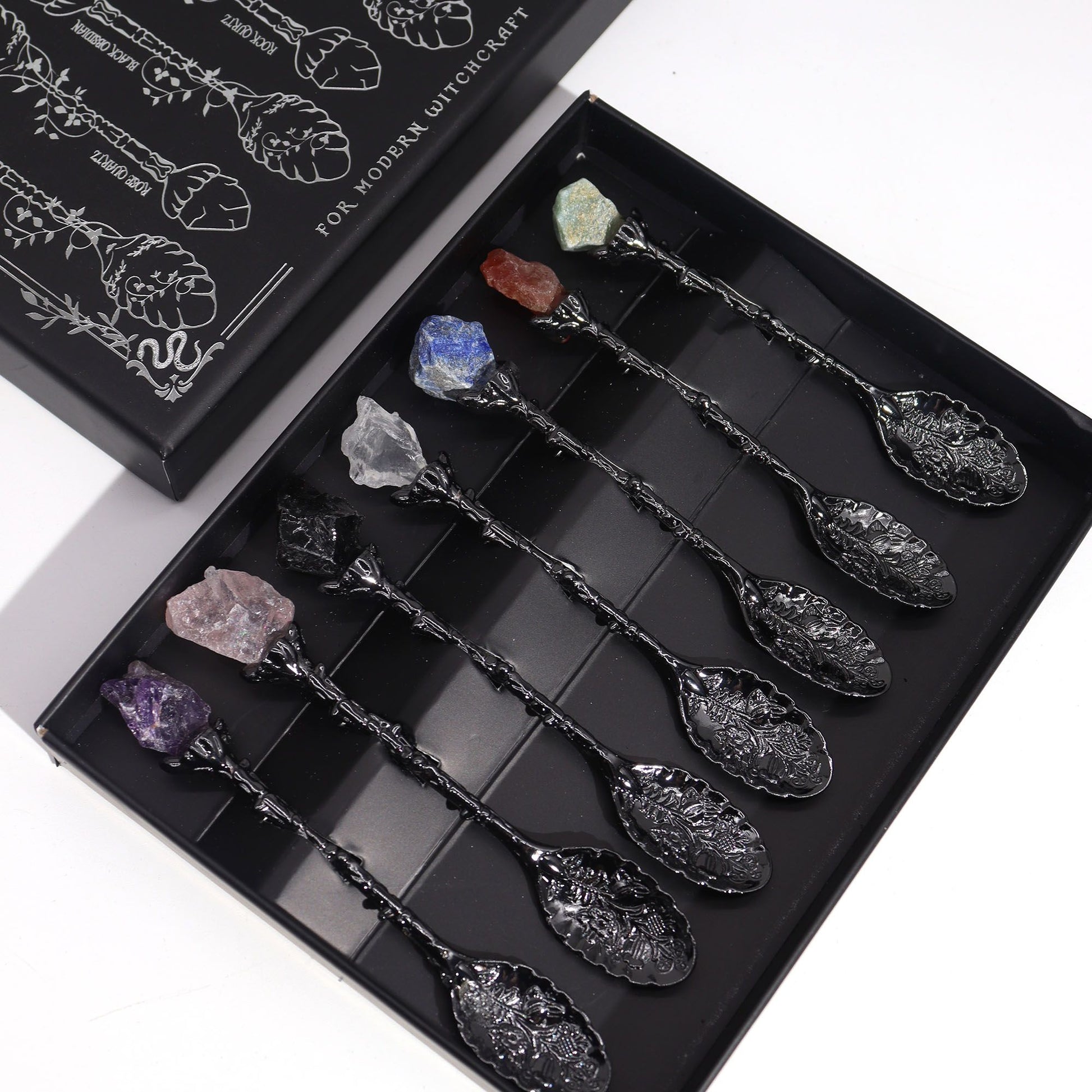 Set of 7 dark silver spoons, each topped with a unique raw gemstone.